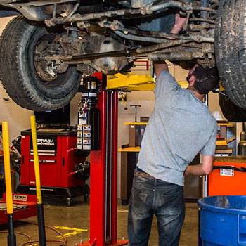 student working under car on lift