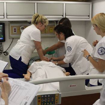 Three medical students working on health manikin