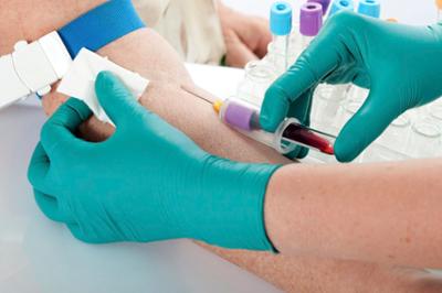 worker drawing blood with green glove on hand