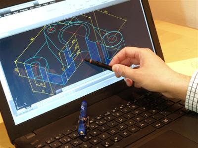 computer screen displaying technical drawing. There is a hand holding a stylus pointing at part of the drawing. 