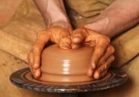 student making a clay pot on a wheel