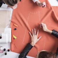 two people working on a piece of fabric tracing a pattern