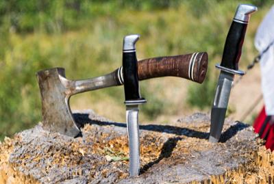 A hatchet and knives plunged into a tree stump.