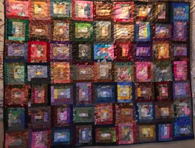 A very colorful quilt, made using blocks and sewn by hand.