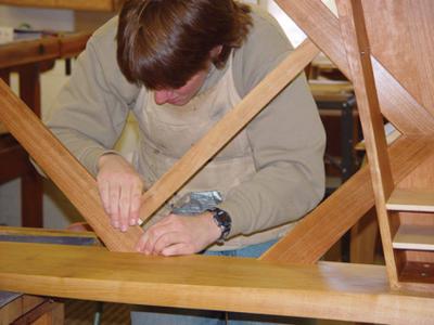 A man working with carpentry tools to build a bench in a woodworking studio.