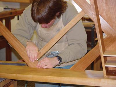 A man is working in a woodshop on a table.