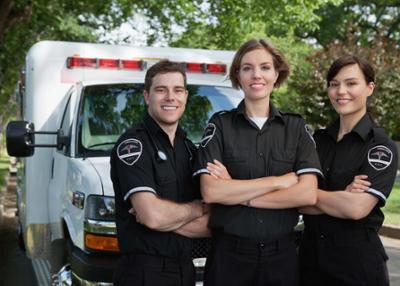 three EMS workers in front of ambulance with arms crossed