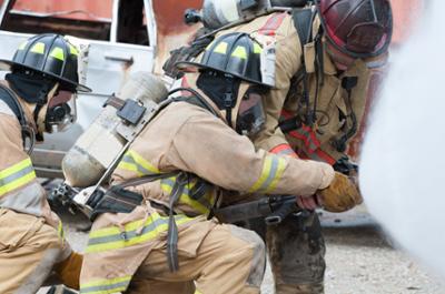 firemen in gear holding hose spraying to the right