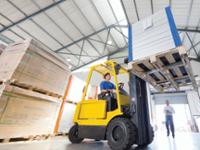 man operating a forklift with large silver box raised on forklift tray
