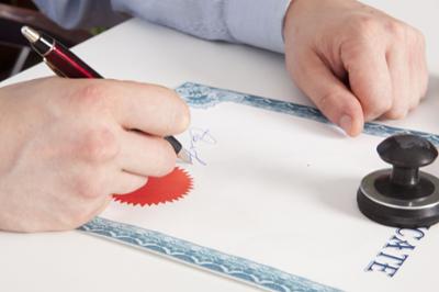 hands on desk with pen signing certificate