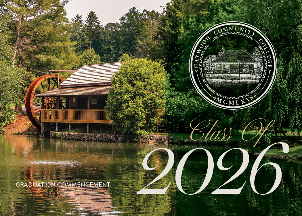 Scenic view of the historic waterwheel and mill building at Haywood Community College, surrounded by lush green trees and reflected in a calm pond. The college seal appears in the upper right corner, and elegant text reads ‘Class of 2026.’ Smaller text at the bottom says ‘Graduation Commencement.’