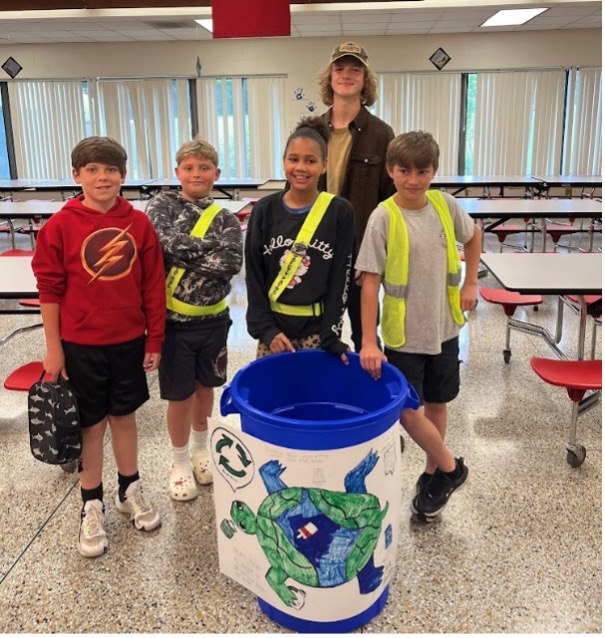 Will Roberts with 4 Lake Junaluska Elementary students by recycling bin in cafeteria