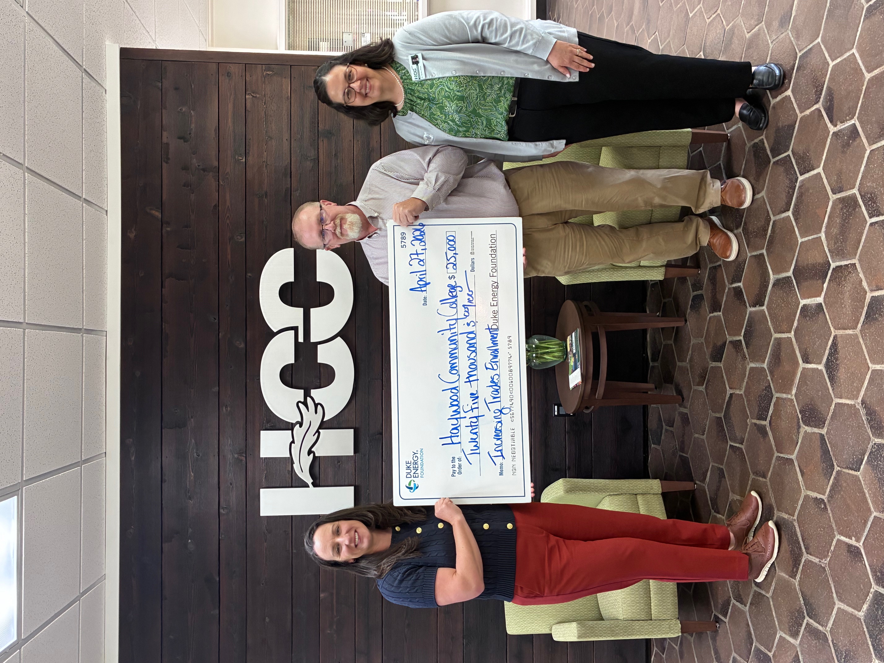 Jennifer Bennett, Doug Burchfield, Shelley White with large check under HCC logo