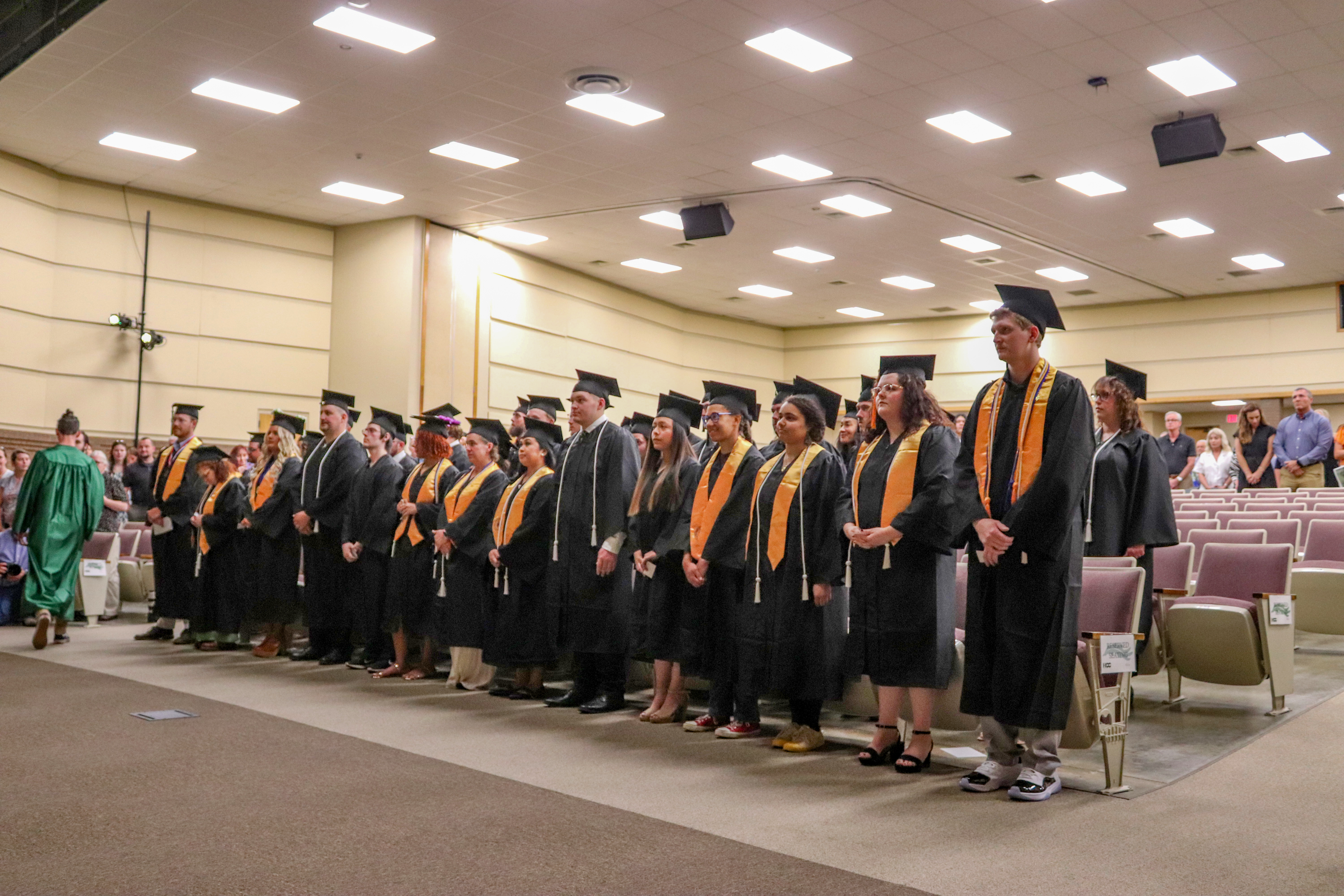 graduates in the front row of the auditorium in their cap and gowns