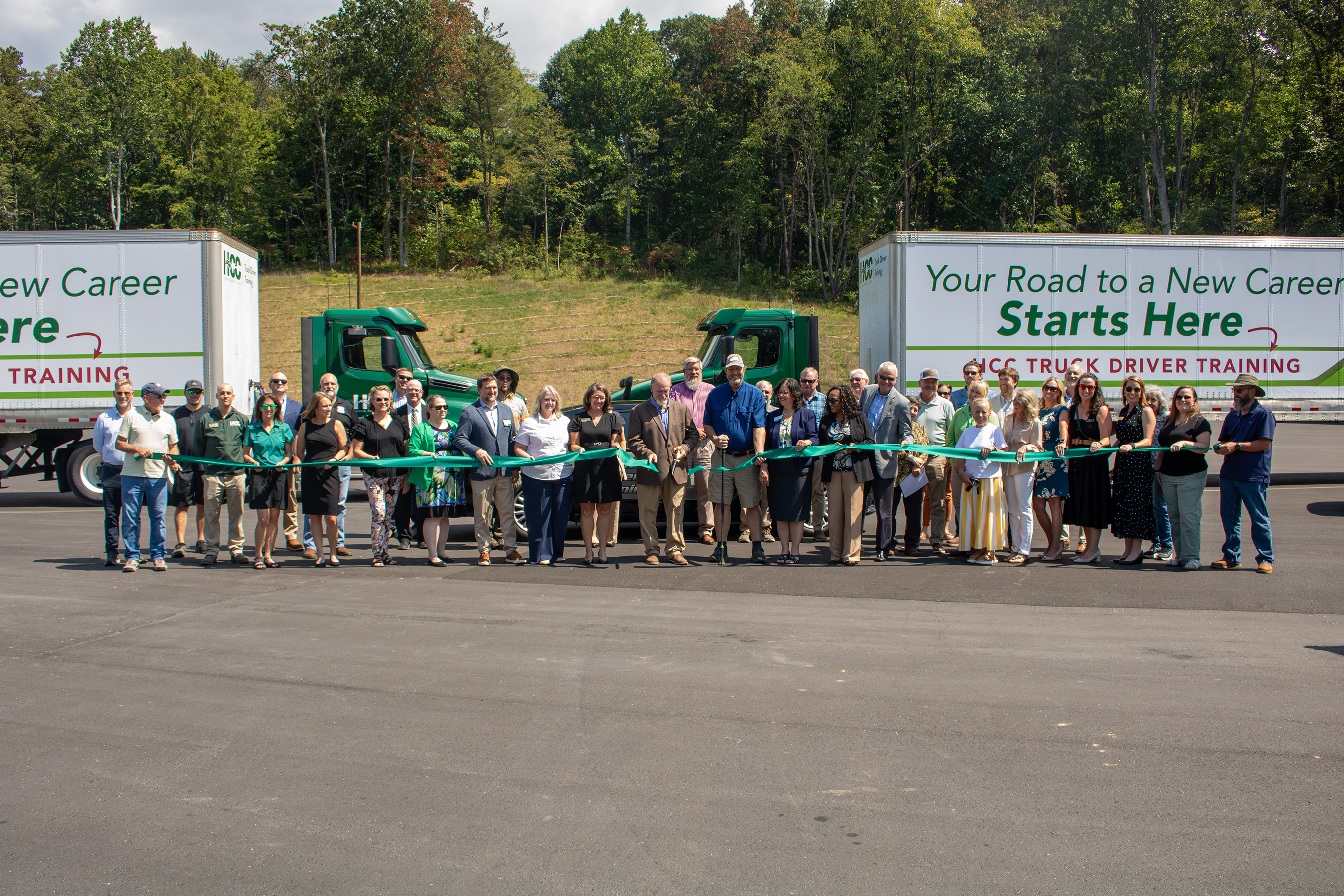 event attendees cutting ribbon in front of cdl trucks