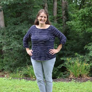 Stephanie Wampler with hands on hips near trees