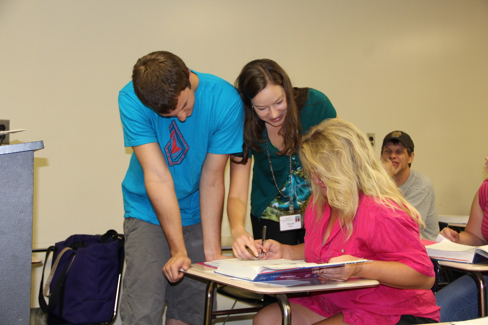 students at desk looking at book