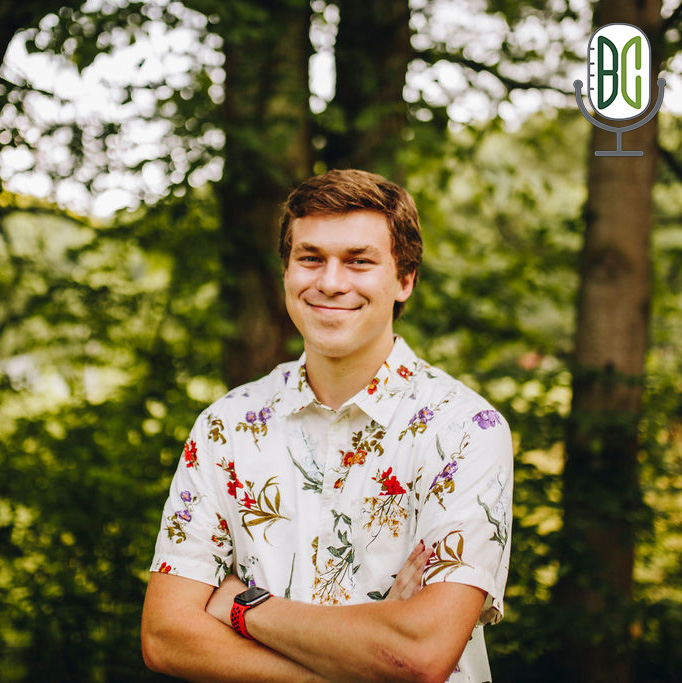 Ethan Hall with arms crossed in front of trees